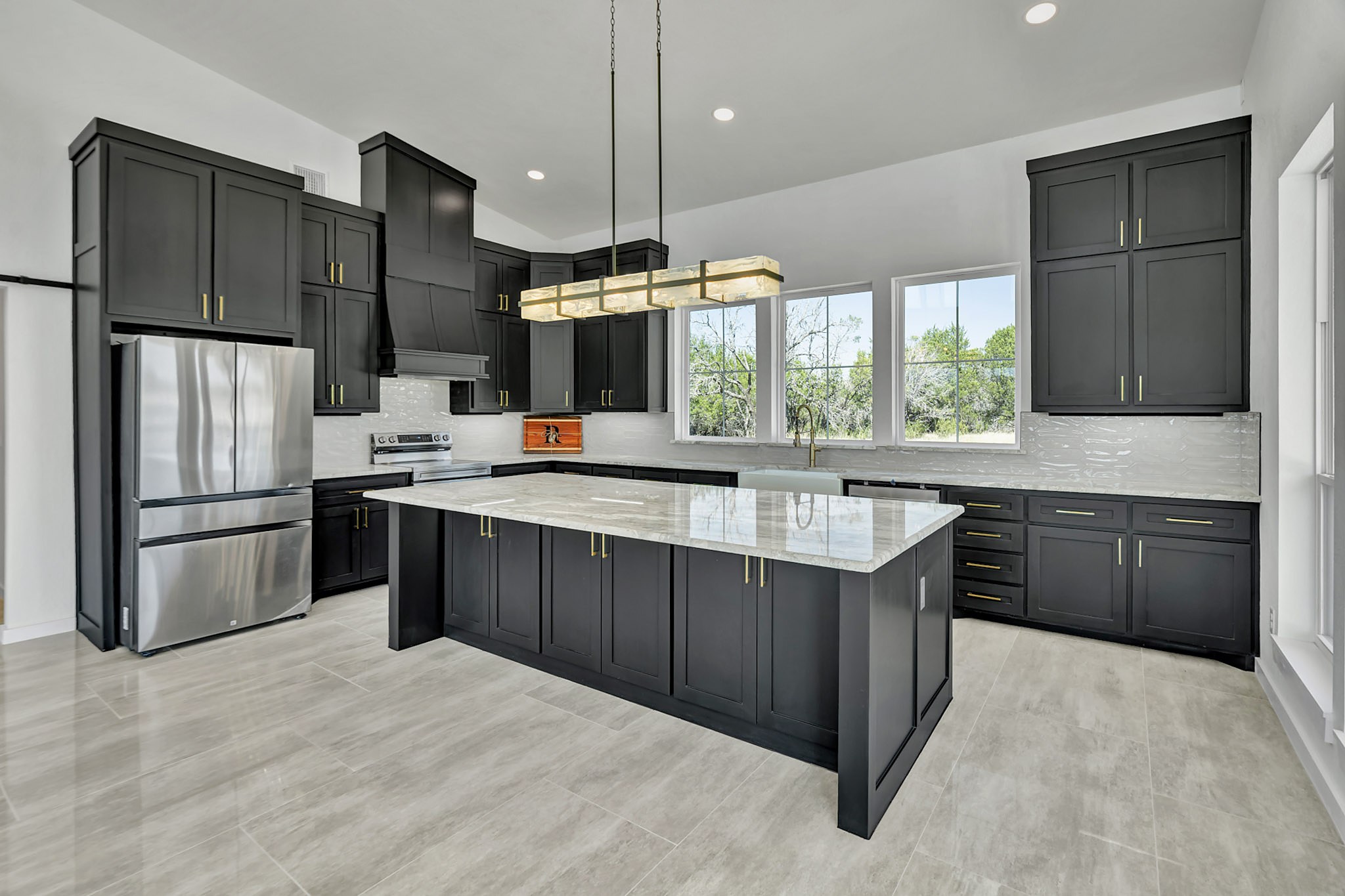 Kitchen with black shaker cabinets and a marble island
