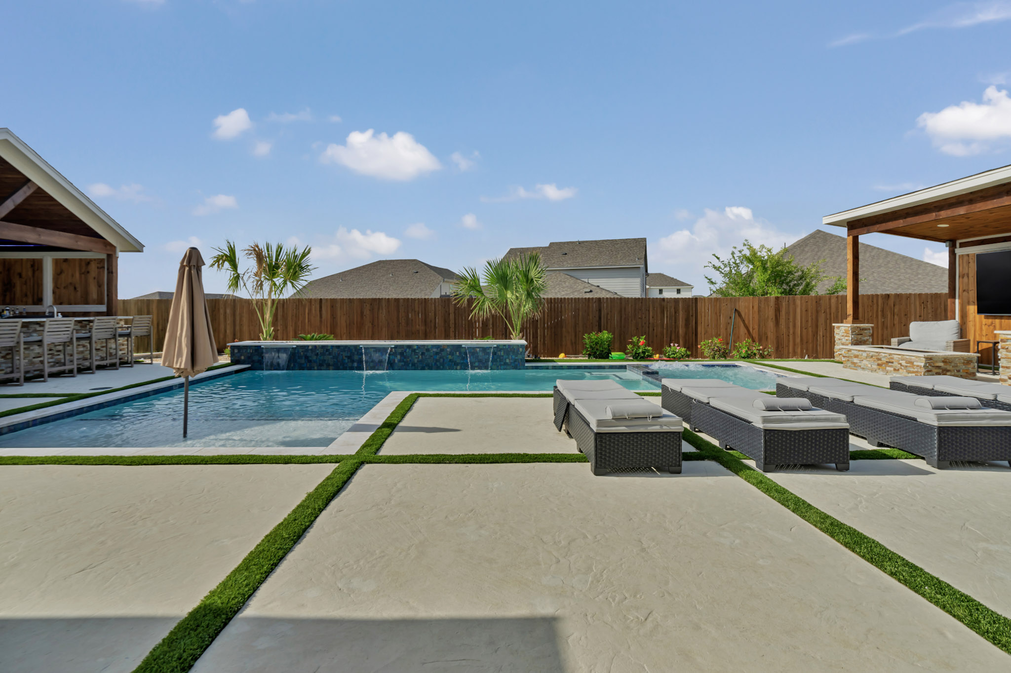 Finished pool with a tiled sheer descent wall, tanning ledge and turf inlaid decking